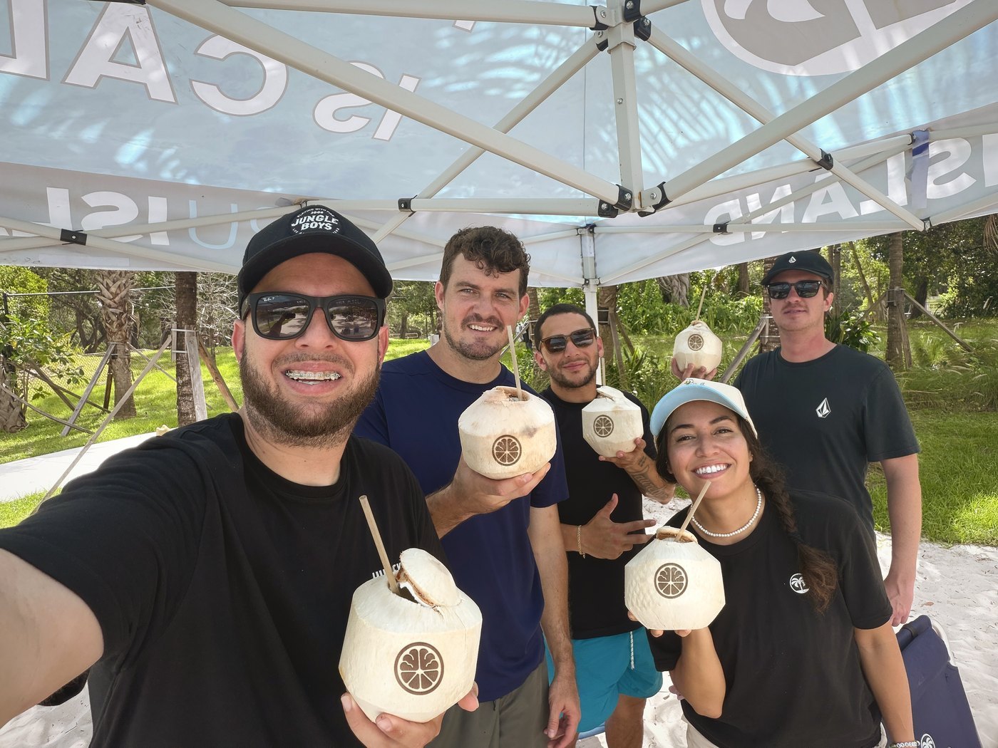 The InvestJuice team outdoors holding branded coconuts