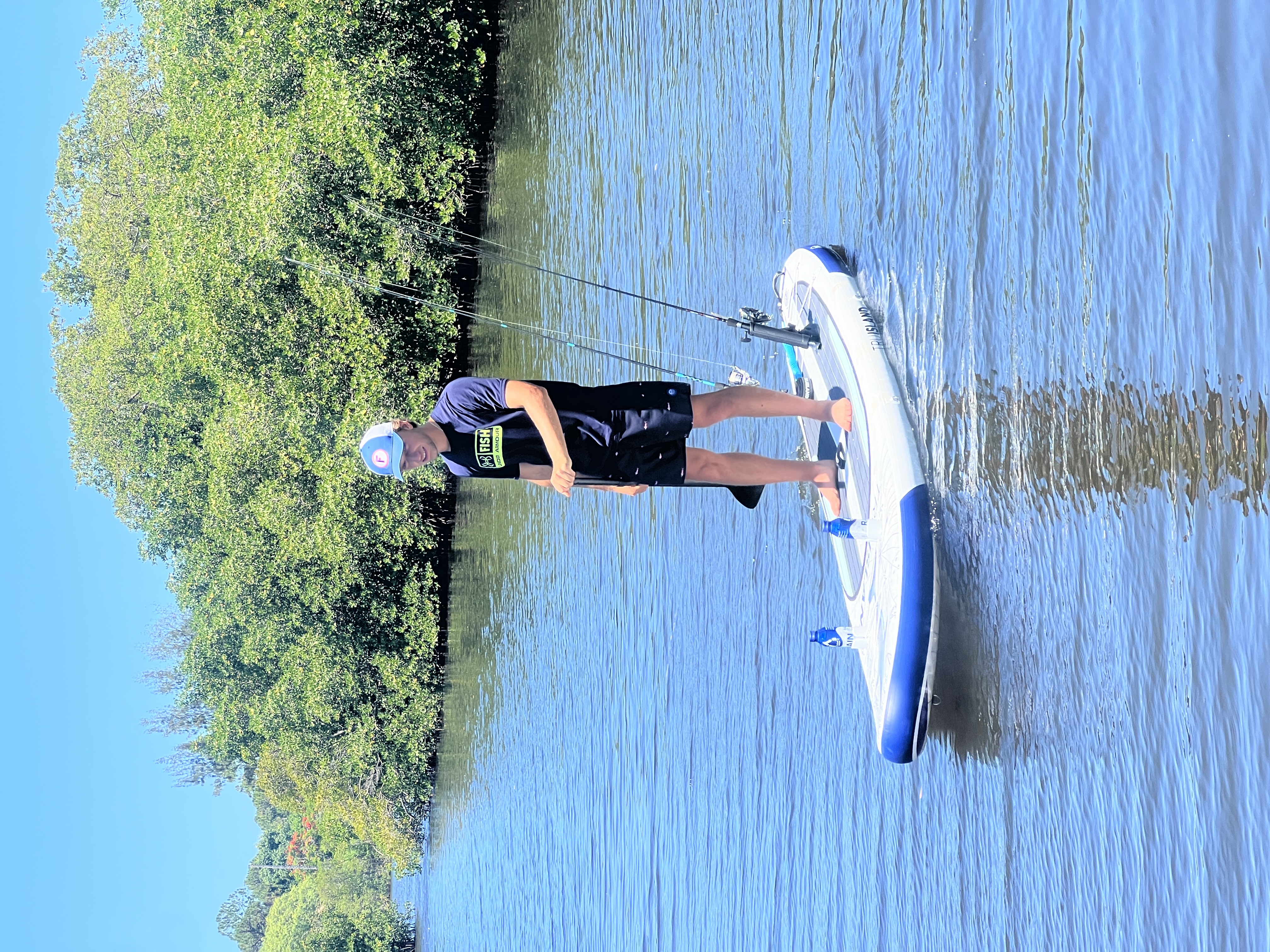 Inflatable fishing SUP with rod holders and bottles on the nose on mangrove water