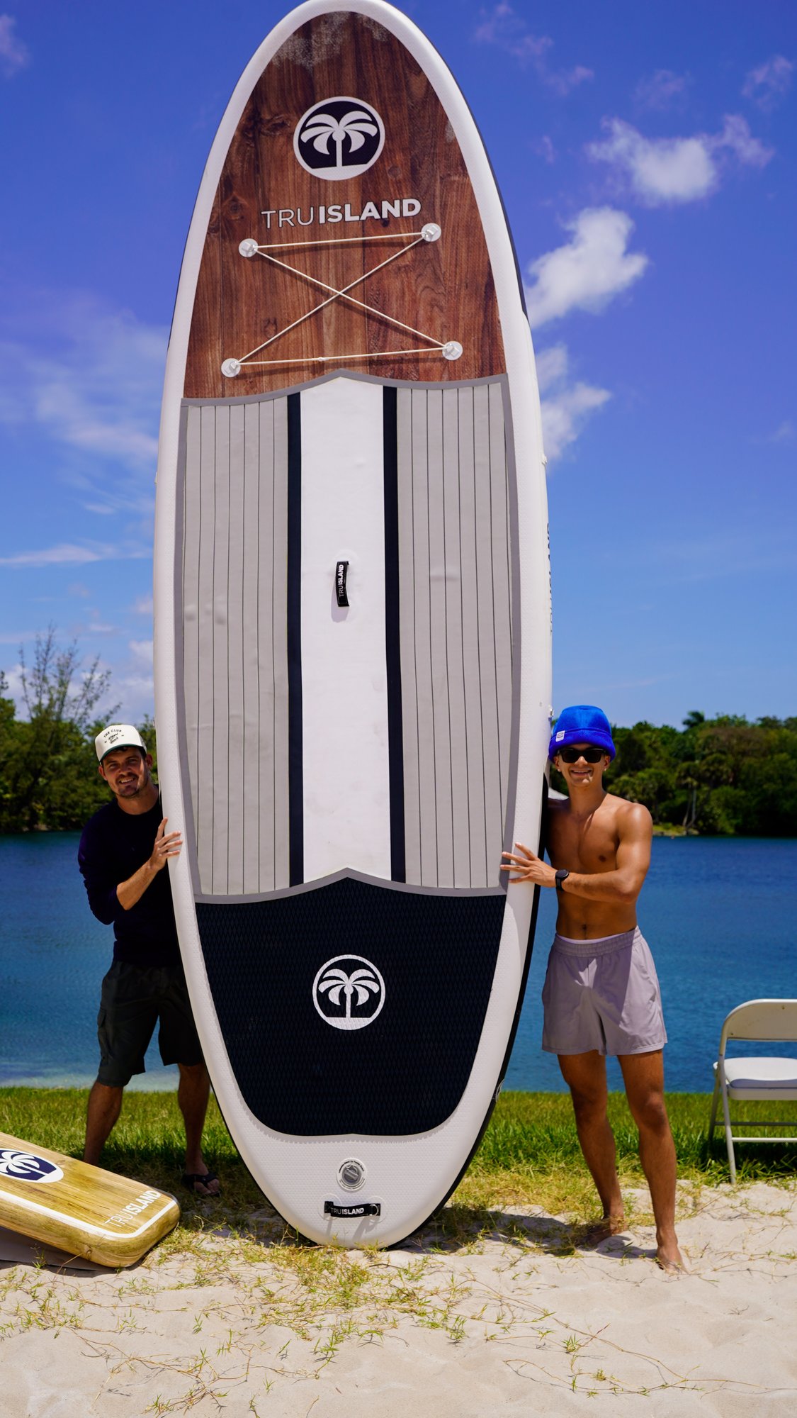 TruIsland SUP held on the beach by two people with palm logo clear on the board